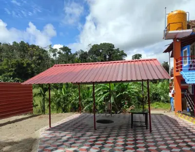 a pavilion with a red roof in front of a building at Lake View Homestay by StayApart in Madikeri