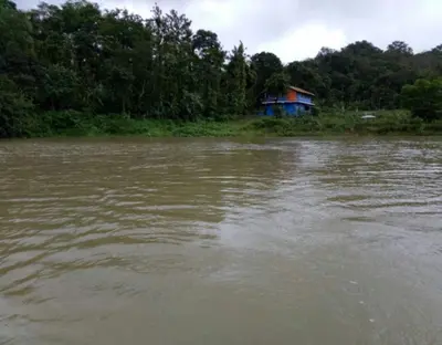 a house sitting on the side of a river at Lake View Homestay by StayApart in Madikeri