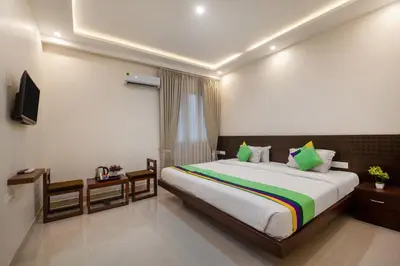 a bedroom with a large bed and a television at Treebo Sans Sarav Kushalnagar, 10 mins to Nisargadhama Island in Madikeri