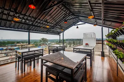 a restaurant with tables and chairs on a balcony at Treebo Sans Sarav Kushalnagar, 10 mins to Nisargadhama Island in Madikeri