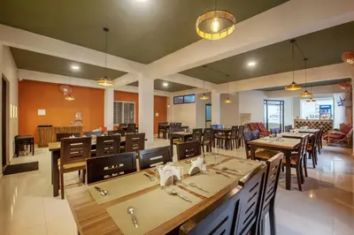 a dining room with wooden tables and chairs at Treebo Sans Sarav Kushalnagar, 10 mins to Nisargadhama Island in Madikeri