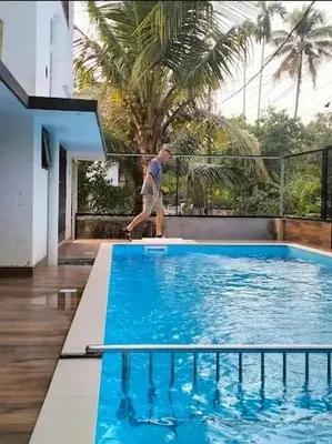 a man is standing next to a swimming pool at Bachan's Casa The Private Pool Villa Cherai in Cherai Beach
