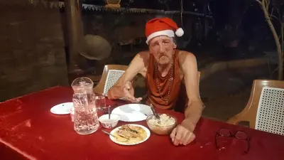 a man in a santa hat eating food at a table at Ambadi's villa -Lake view resort in Pallipuram
