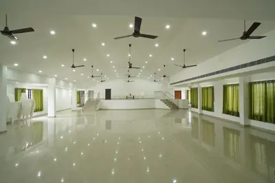 a large white room with chairs and ceiling fans at SN ROOMS in Perumbavoor