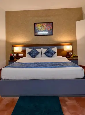 a bedroom with a large white bed with blue pillows at Adrak Mountain Mist Forest Resort in Pulpally