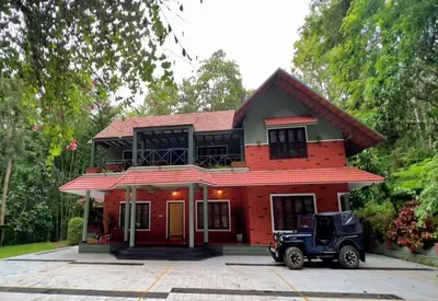 a car parked in front of a red house at Adrak Mountain Mist Forest Resort in Pulpally