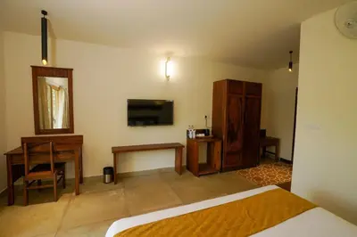a bedroom with a bed and a desk and a television at Maple Ash Resort in Vayittiri