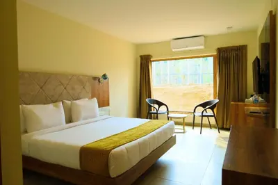 a hotel room with a bed and a table and a window at Maple Ash Resort in Vayittiri