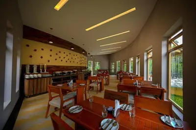 a restaurant with wooden tables and chairs in a room at Maple Ash Resort in Vayittiri