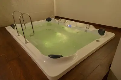 a bath tub with green water in it on a wooden floor at Maple Ash Resort in Vayittiri