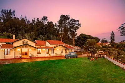 a house with a car parked in the yard at Rosewood by Nature Resorts and Stays in Ooty