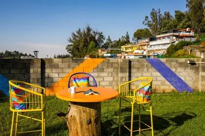 a table and two chairs sitting next to a tree stump at goSTOPS Ooty in Ooty
