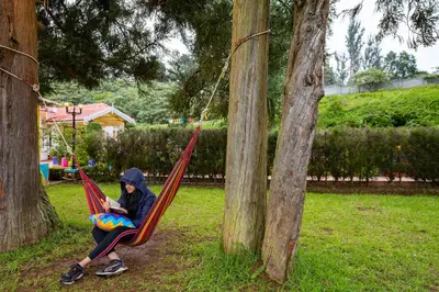 a woman sitting in a hammock in a park at goSTOPS Ooty in Ooty