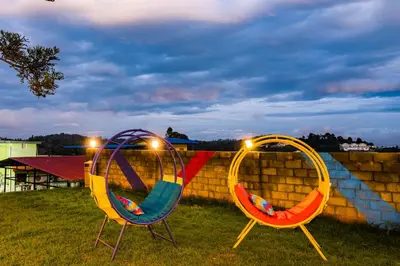 two chairs sitting in the grass with lights on them at goSTOPS Ooty in Ooty