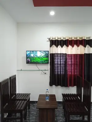 a room with two chairs and a tv on a wall at Leo's Residency Coorg in Kushālnagar