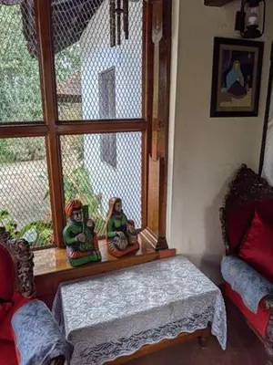 a room with a window with two figurines on a bench at Sardar Bahadur's Heritage Bungalow Estate Stay in Napoklu