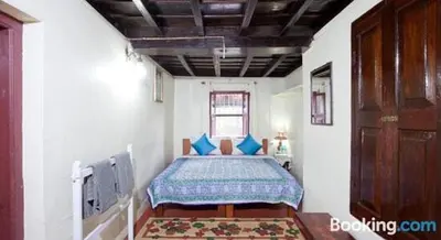 a bedroom with a bed with blue pillows at Sardar Bahadur's Heritage Bungalow Estate Stay in Napoklu