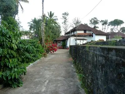 a road leading to a house next to a fence at Sardar Bahadur's Heritage Bungalow Estate Stay in Napoklu