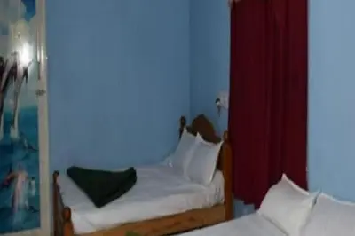 a bedroom with two beds and a red curtain at Green Coorg by StayApart, Madikeri in Madikeri