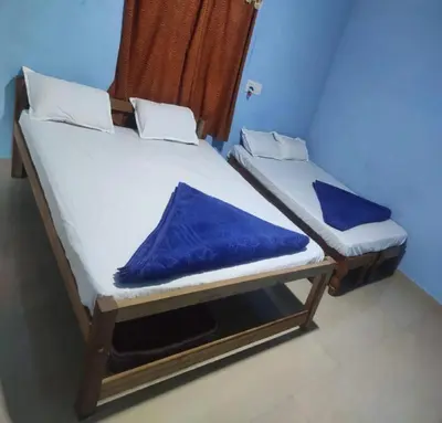two twin beds in a room with blue walls at Green Coorg by StayApart, Madikeri in Madikeri