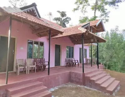 a pink house with a porch and a patio at Green Coorg by StayApart, Madikeri in Madikeri
