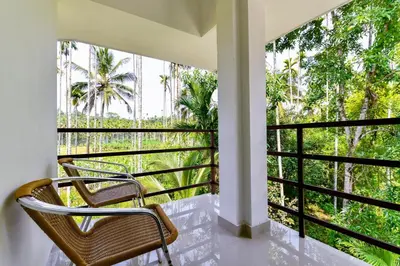 a balcony with two chairs and a view of trees at CentreHome Villa Wayanad in Meenangadi