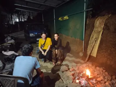 a couple of people sitting around a fire at CentreHome Villa Wayanad in Meenangadi