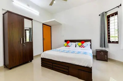 a bedroom with a bed and a wooden cabinet at CentreHome Villa Wayanad in Meenangadi