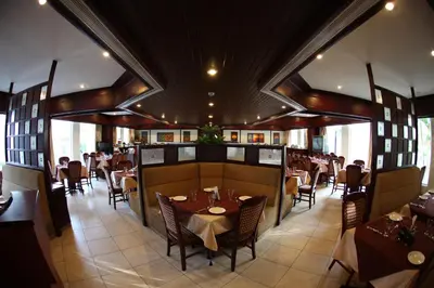 a restaurant with wooden ceilings and tables and chairs at RATHNA RESIDENCY in Coimbatore