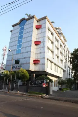 a tall white building with windows on a street at RATHNA RESIDENCY in Coimbatore
