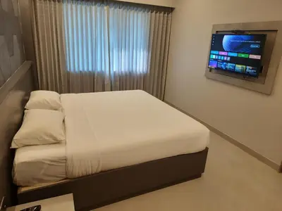a bedroom with a bed with a television on the wall at RATHNA RESIDENCY in Coimbatore