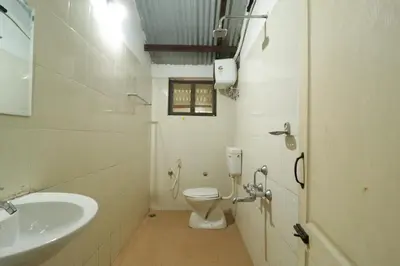 a white bathroom with a toilet and a sink at Havon Plantation Resorts in Varagampadi