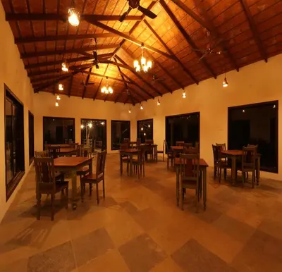 a dining room with wooden tables and chairs at Havon Plantation Resorts in Varagampadi