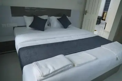a large white bed with blue pillows in a room at Yelza Hotel and Residence in Alwaye
