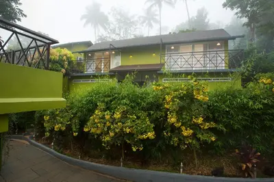 a green house with yellow flowers in front of it at Amrezy Resort and Spa by Stride, Wayanad in Vythiri