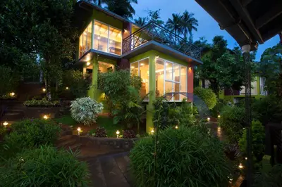 a house with lights in a garden at night at Amrezy Resort and Spa by Stride, Wayanad in Vythiri