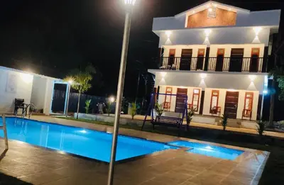 a house with a swimming pool at night at The Lavender Resort Waynad in Vaduvanchal