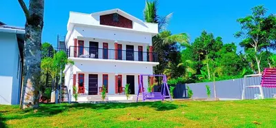 a white house with a fence and a yard at The Lavender Resort Waynad in Vaduvanchal