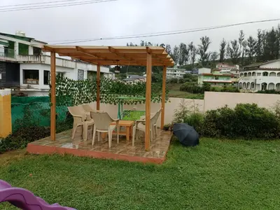 a wooden gazebo with a table and chairs in a yard at Rose Garden Enclave for Families & Executives in Ooty