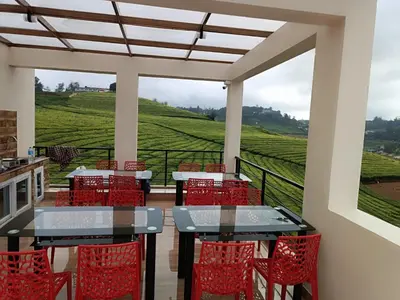a patio with red chairs and tables and a view of a vineyard at Rose Garden Enclave for Families & Executives in Ooty