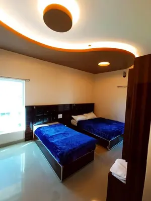 two beds in a room with blue sheets at Rose Garden Enclave for Families & Executives in Ooty