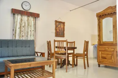 a living room with a couch and a table and chairs at Down House 19 Ooty - TEYT HOLIDAYS in Ooty