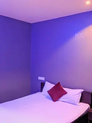 a bedroom with a white bed with a purple wall at FAAZ Residency in Kozhikode