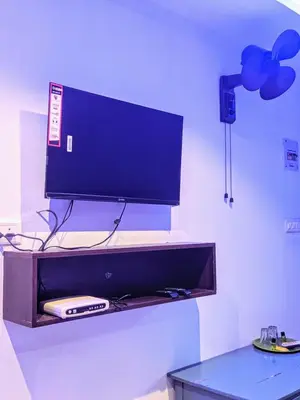 a flat screen tv sitting on a wall with a table at FAAZ Residency in Kozhikode