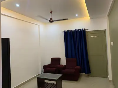 a living room with a chair and a table at FAAZ Residency in Kozhikode