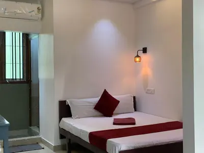 a small bedroom with a bed with a red pillow at FAAZ Residency in Kozhikode