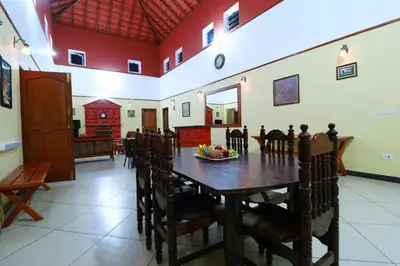 a dining room with a wooden table and chairs at SaffronStays Coorg Toddy Farms, Coorg in Madikeri
