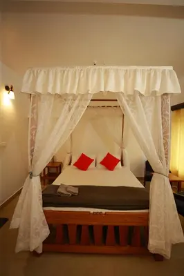 a bedroom with a canopy bed with red pillows at Ayla Homes in Madikeri
