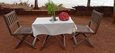 two chairs with a table with a vase of flowers at Perch by the sea in Kannur