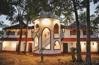 an old house with trees in front of it at Vala House in Cherai Beach